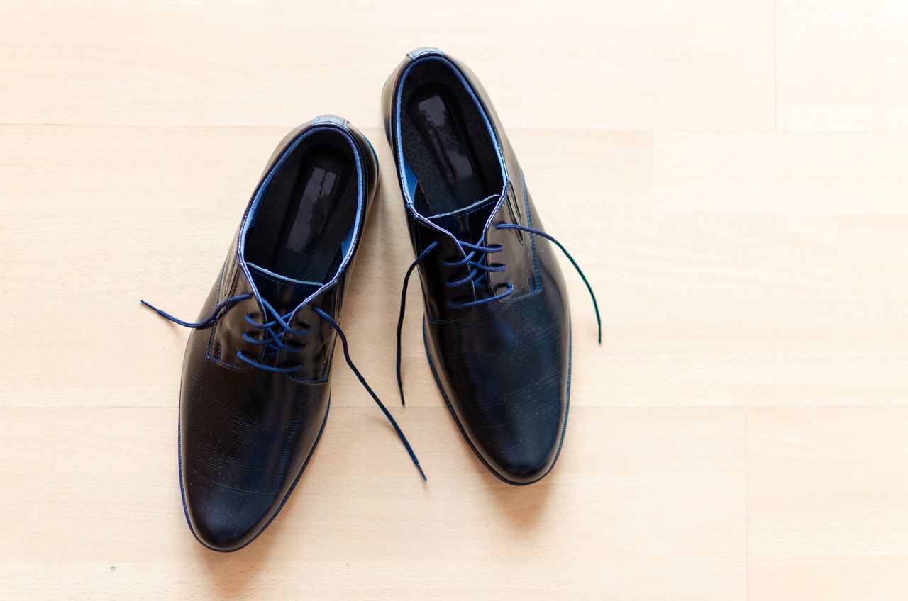 Mastering the First Impression: Your intriguing post title goes here Pair of stylish black leather shoes with blue laces on a wooden floor.